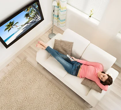 Chica en un sofá viendo tv anclada a una pared de tablaroca